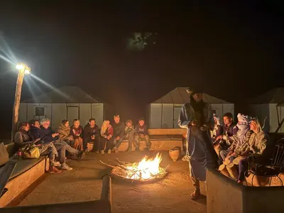 a group of people sitting around a fire at Dream luxury camp in Merzouga
