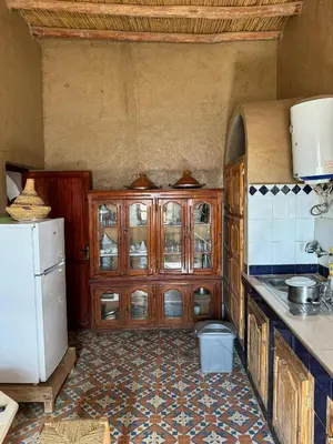 a kitchen with wooden cabinets and a white refrigerator at berber desert home for rent in Merzouga