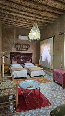 a large room with two beds and a table at berber desert home for rent in Merzouga