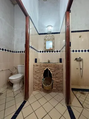 a bathroom with a toilet and a brick fireplace at berber desert home for rent in Merzouga