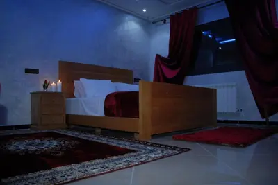 a bedroom with a bed with a wooden bed frame and a dresser at Moonrise Villa VIP Midelt in Midelt