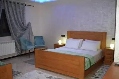 a bedroom with a bed and two chairs and a television at Moonrise Villa VIP Midelt in Midelt