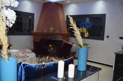 a living room with a fireplace and blue vases with flowers at Moonrise Villa VIP Midelt in Midelt
