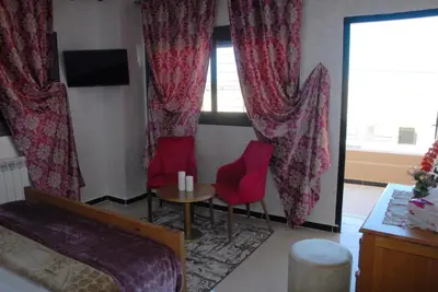 a hotel room with a bed and two red chairs at Moonrise Villa VIP Midelt in Midelt