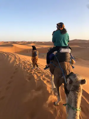 a woman riding on the back of a camel in the desert at Royal Dune Private Tent in Merzouga