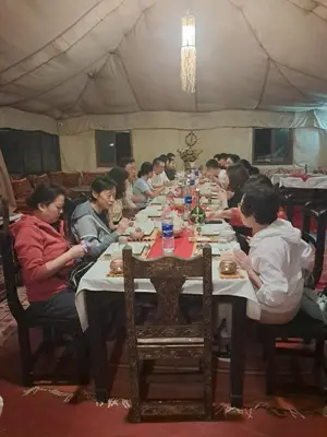 a group of people sitting at a long table at Royal Dune Private Tent in Merzouga