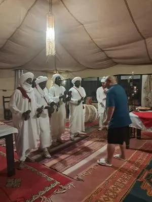 a man standing in front of a group of people in a tent at Royal Dune Private Tent in Merzouga