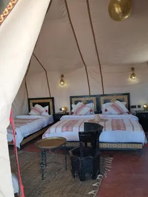 a room with two beds and a table in a tent at Royal Dune Private Tent in Merzouga