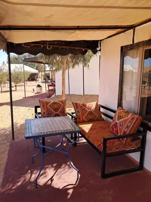 a picnic table and chairs under an umbrella at Royal Dune Private Tent in Merzouga