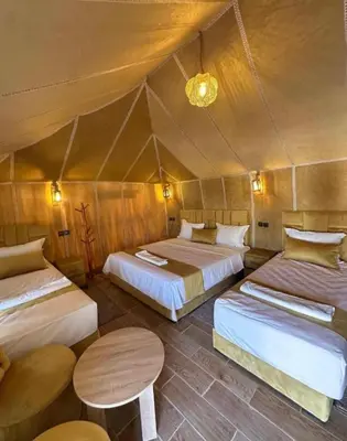 a room with two beds and a table in a tent at Sunshine luxury tent in Merzouga