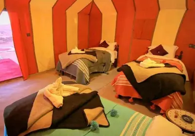 two beds in a room with red and yellow walls at Sunshine luxury tent in Merzouga
