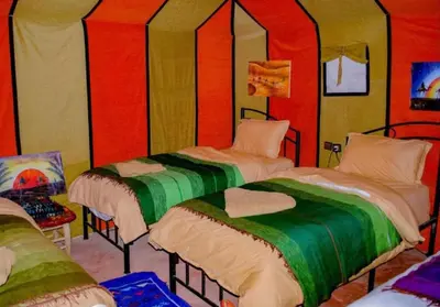 two beds in a room with red and green at Sunshine luxury tent in Merzouga