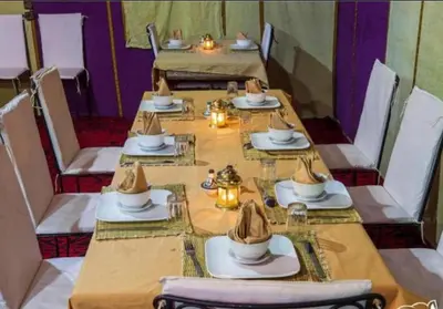a long table with plates and hats on top at Sunshine luxury tent in Merzouga