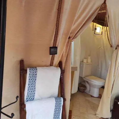 a small bathroom with a toilet and a curtain at Authentic Desert Camp in Merzouga