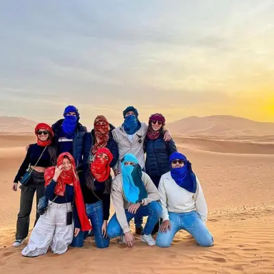 a group of people posing for a picture in the desert at Authentic Desert Camp in Merzouga