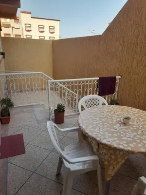 a patio with a table and chairs on a balcony at Appartement meublé ennasr49 in Khenifra