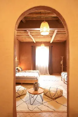 a room with two beds and a table and a window at Riad Dar Tiziri in Zagora