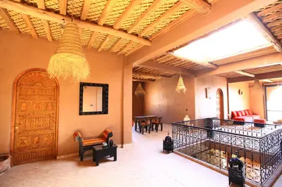 a living room with chairs and a large wooden door at Riad Dar Tiziri in Zagora