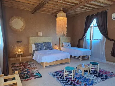a bedroom with two beds and chairs and a window at Riad Dar Tiziri in Zagora