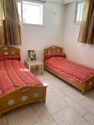 two beds in a room with red sheets at Appartement 2 chambres avec lit bébé in Fès