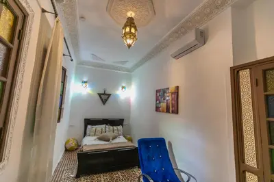 a bedroom with a bed and a blue chair at Riad bel kaid fes in Fès