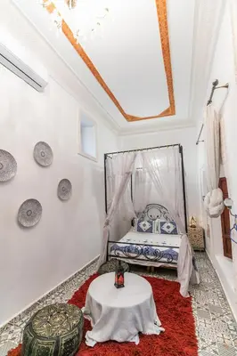 a bedroom with a bed and a table on a red rug at Riad bel kaid fes in Fès