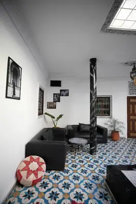 a living room with black couches and a rug at Riad bel kaid fes in Fès