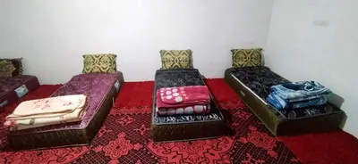 three beds sitting in a room with a red carpet at Gite taouraout in Midelt