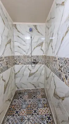 a bathroom with a marble shower with a tile floor at Gite taouraout in Midelt