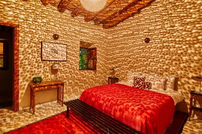 a bedroom with a bed with a red blanket and a table at Dar Imiri in Ourika