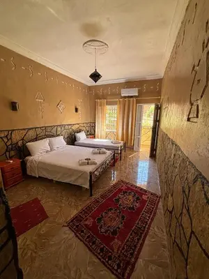 a large bedroom with two beds and a rug at Riad Lalla in Tinerhir