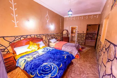 a bedroom with a bed with a blue comforter at Riad Lalla in Tinerhir