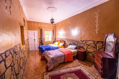 a bedroom with two beds and a tv in it at Riad Lalla in Tinerhir