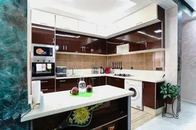 a kitchen with brown cabinets and a washer and dryer at Appartement Emeraude - Calme, Moderne & Sécurisé in Fès