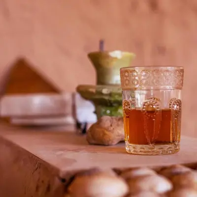 a glass of tea sitting on top of a table at Dar Nomad Tagounite in Zagora