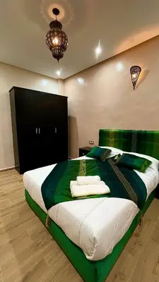 a bedroom with a large bed with green and white sheets at Stay In Fez in Fès