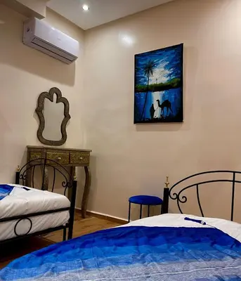 a bedroom with two beds and a painting on the wall at Stay In Fez in Fès