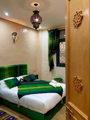 a bedroom with a bed with green sheets and a chandelier at Stay In Fez in Fès