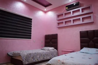 a bedroom with pink walls and two beds in it at Villa world Marrakech in Marrakech