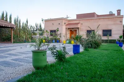 a building with potted plants in front of a yard at Villa world Marrakech in Marrakech