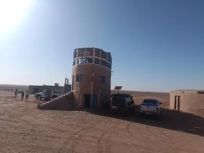 a building in the middle of a desert with cars parked at Bivouac beauté du désert in Mhamid