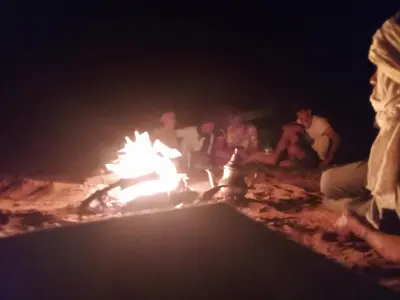 a group of people sitting around a campfire at night at Bivouac beauté du désert in Mhamid