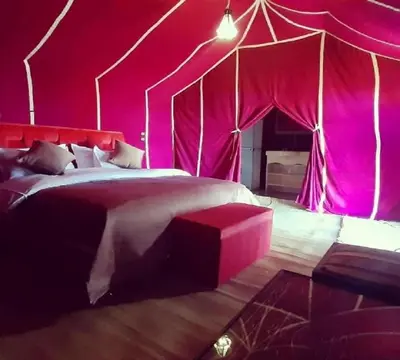 a bedroom with a bed in a pink tent at Erg Chebbi Desert Luxury Camp in Merzouga