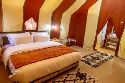 a bedroom with a bed in a tent at Erg Chebbi Desert Luxury Camp in Merzouga