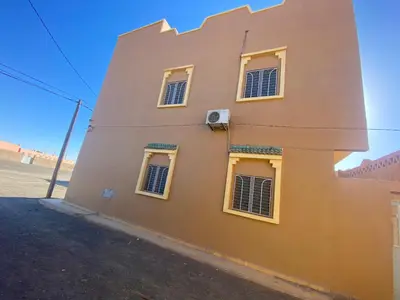 a building with yellow windows on the side of it at Apartement Rachid in Merzouga