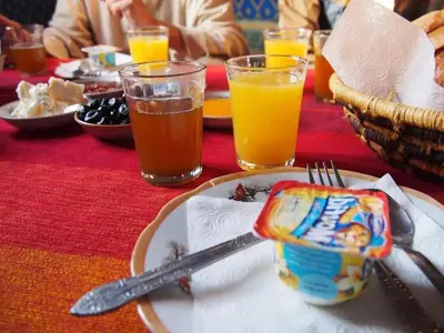 a table with a plate of food and glasses of orange juice at Chegaga Desert Trips in Mhamid