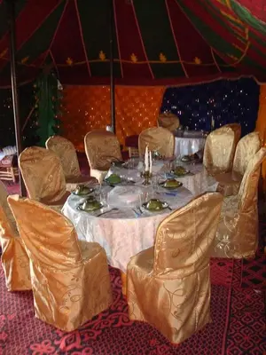 a table and chairs in a room with a tent at Chegaga Desert Trips in Mhamid