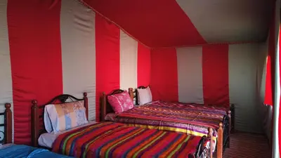 two beds in a room with red and white walls at Chegaga Desert Trips in Mhamid
