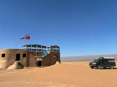 a helicopter flying over a building in the desert at Titanic hôtel restaurant & désert excursions lac irik in Foum Zguid