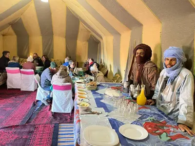 a group of people sitting at a long table at Titanic hôtel restaurant & désert excursions lac irik in Foum Zguid